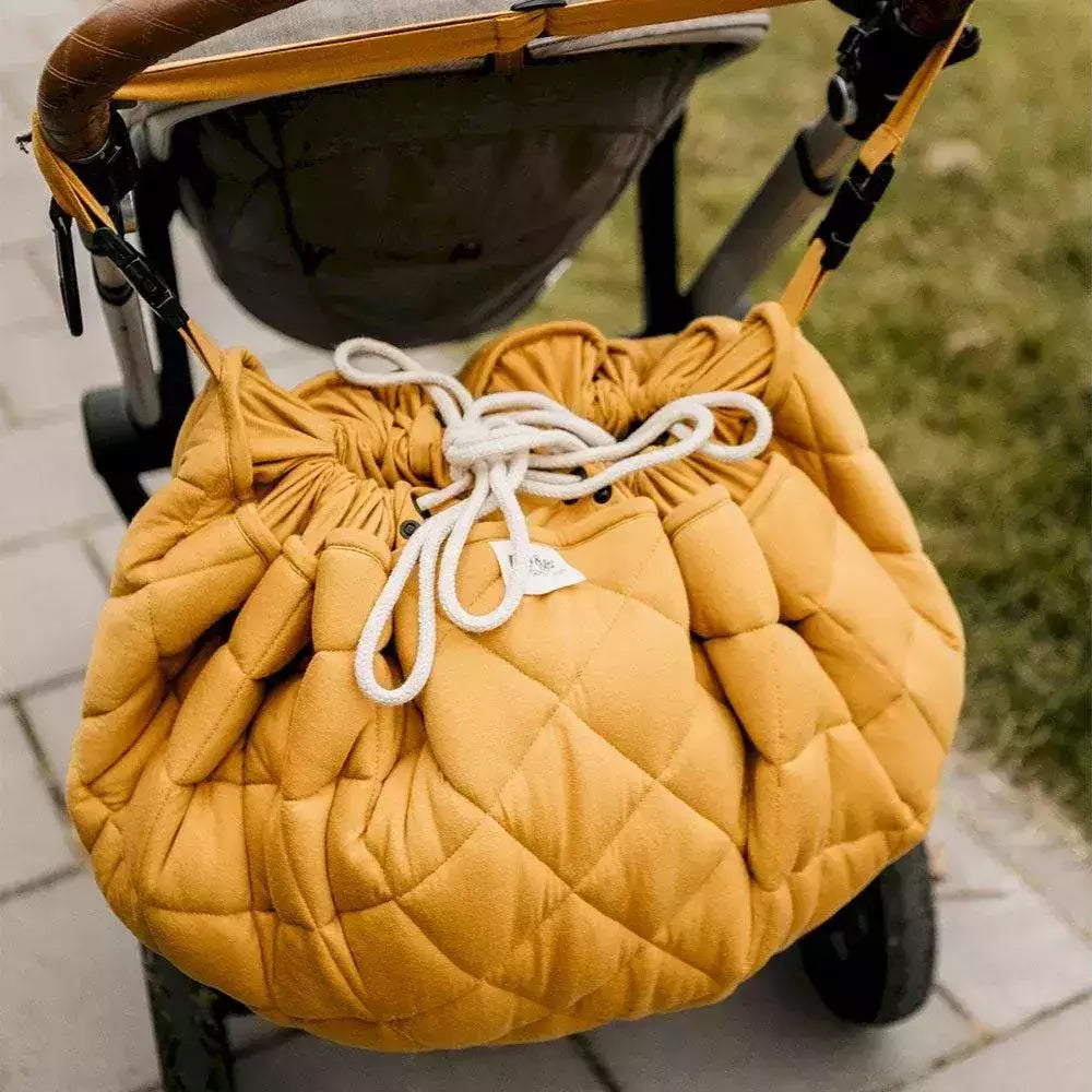 Tappeto Gioco Organic Soft Play&Go Mustard Chai Tea appeso al passeggino