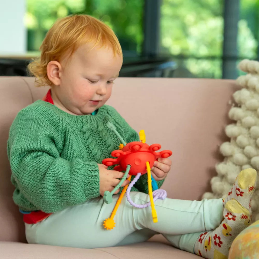 Bambina con in mano il Pianeta Sensoriale in Silicone Tickit Arcobaleno