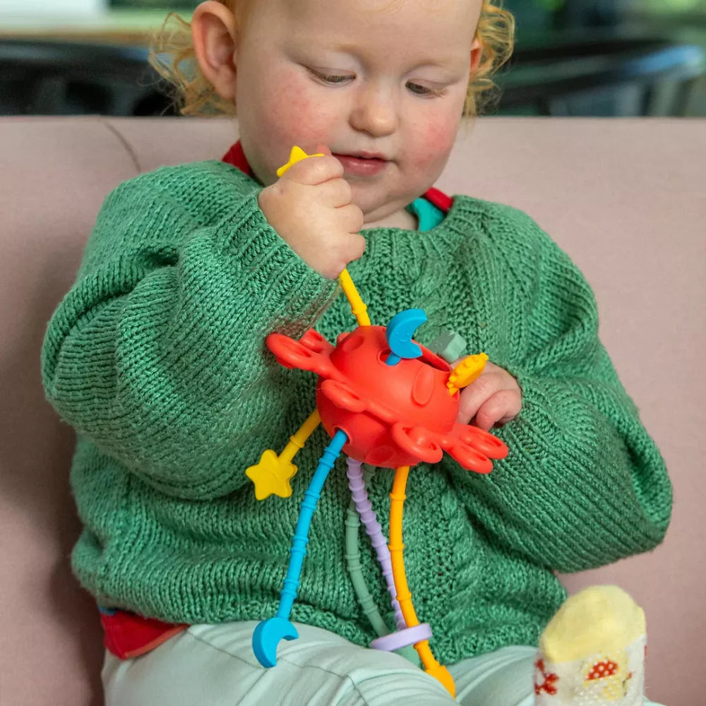 Bambina che usa le zip del Pianeta Sensoriale in Silicone Tickit Arcobaleno