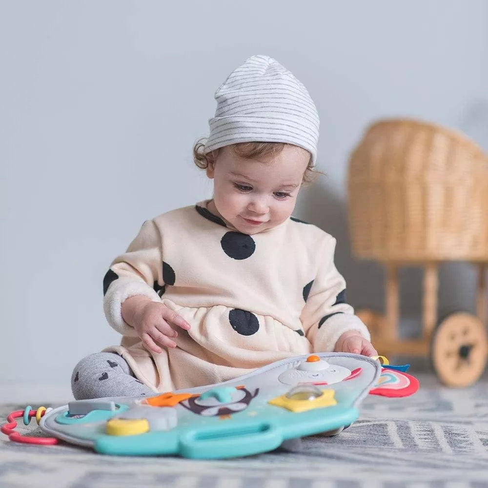 Bambina usa il Pannello Attività Sensoriali North Pole Taf Toys da seduta