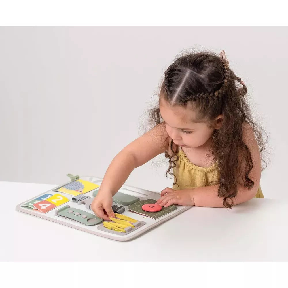 Bambina allaccia i lacci sul Pannello Motricità Fine Taf Toys