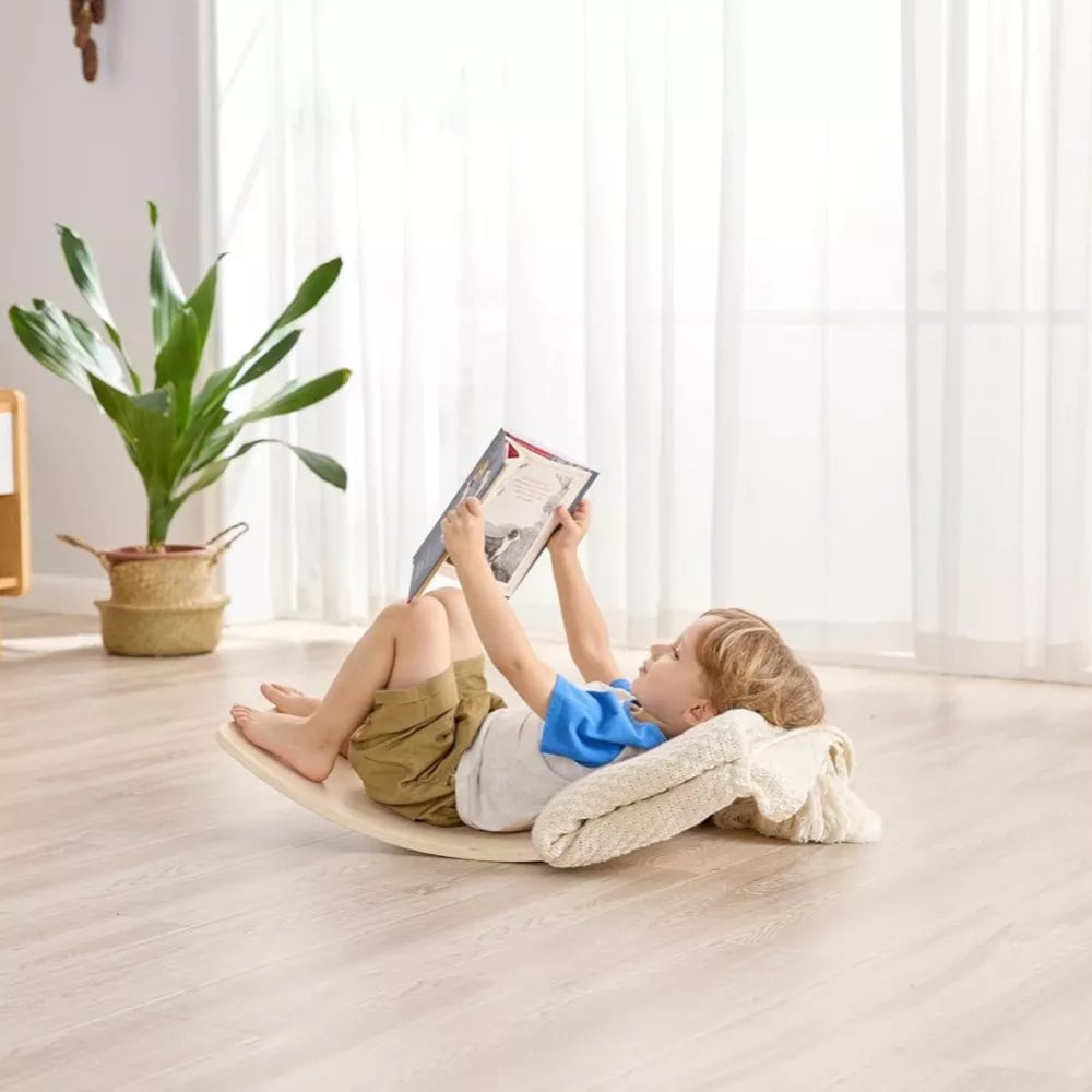 Bambino sdraiato sulla balance board del Cavallo a Dondolo 2 in 1 Hape
